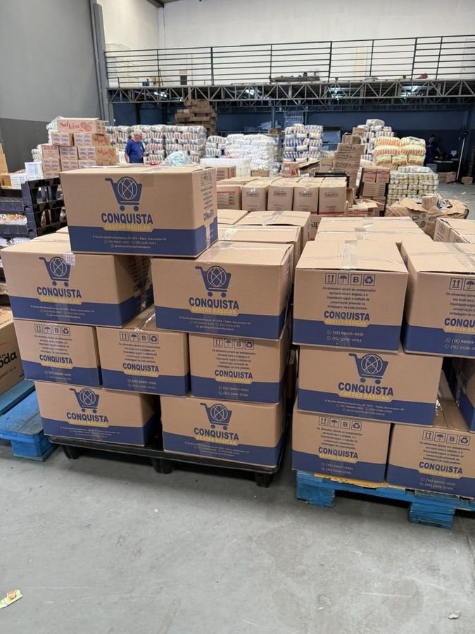 Galpão da Conquista Distribuidora com paletes de cestas básicas empilhadas em Sorocaba